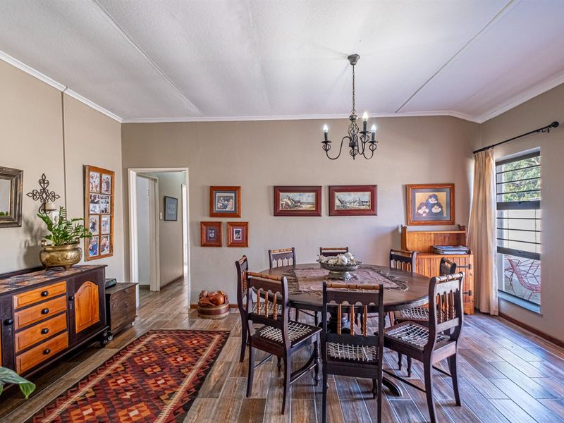 A dining room featuring tiled flooring, a central chandelier, and natural light from a side window.