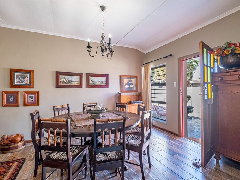 A dining room featuring tiled flooring, a decorative wrought iron chandelier, and a characterful stained glass door leading to the exterior.