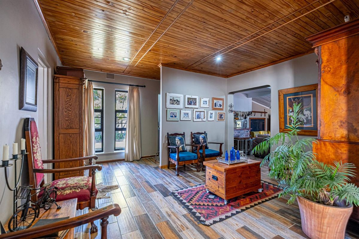 A spacious living area featuring warm timber plank ceilings, wood-look tile flooring, and recessed lighting, creating a cozy and inviting atmosphere.