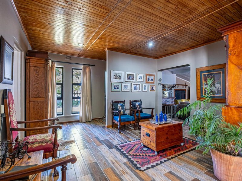 A spacious living area featuring warm timber plank ceilings, wood-look tile flooring, and recessed lighting, creating a cozy and inviting atmosphere.