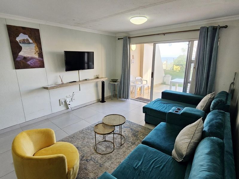 A bright living room featuring tiled flooring and large sliding glass doors that provide direct access to an outdoor patio area.