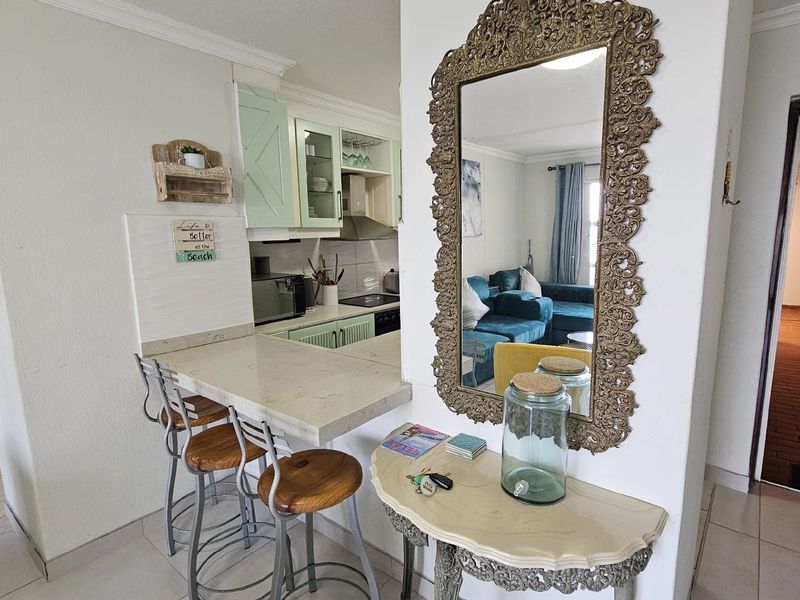Open plan kitchen featuring a breakfast bar counter, light-toned cabinetry, and integrated cooking appliances, seamlessly connecting to the living area.