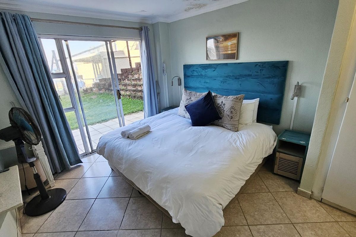 Bedroom featuring tiled flooring and sliding glass doors providing direct access to a private patio and garden area.