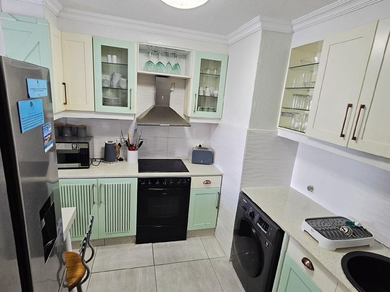 A well-appointed kitchen featuring light-toned cabinetry, a built-in oven with extractor fan, tiled flooring, and integrated appliance spaces.