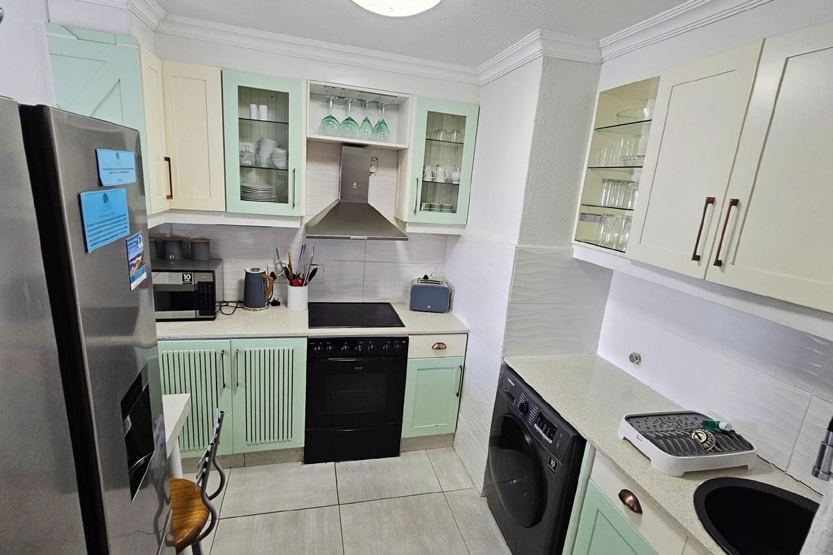 A well-appointed kitchen featuring light-toned cabinetry, a built-in oven with extractor fan, tiled flooring, and integrated appliance spaces.
