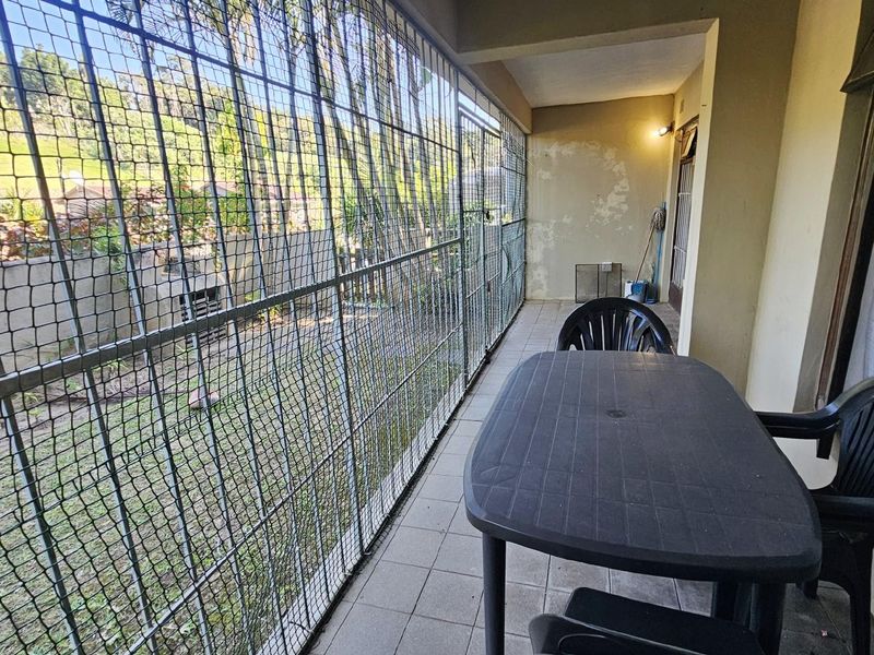 A covered patio area featuring tiled flooring and a full-length metal security mesh enclosure overlooking the rear garden.