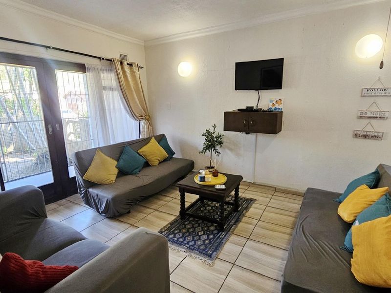 A living room featuring tiled flooring and double glass doors leading to an outdoor area, providing natural light and access to the exterior.