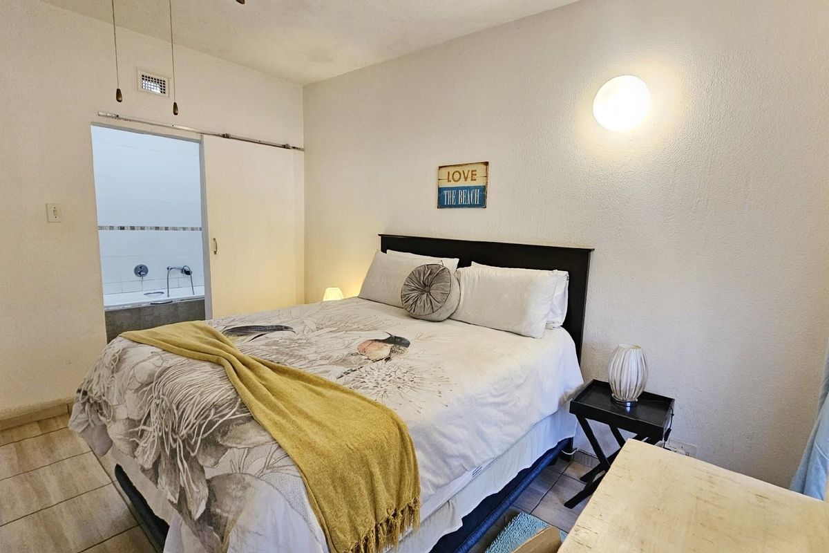 A bedroom featuring tiled flooring and a sliding door providing direct access to an en-suite bathroom.