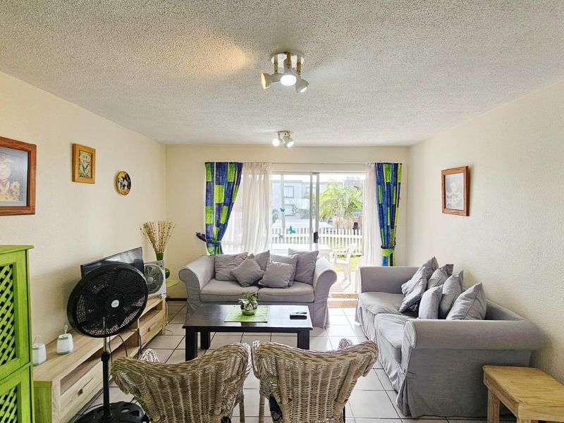 A comfortable living room featuring tiled flooring and sliding glass doors that provide natural light and access to an outdoor patio area.