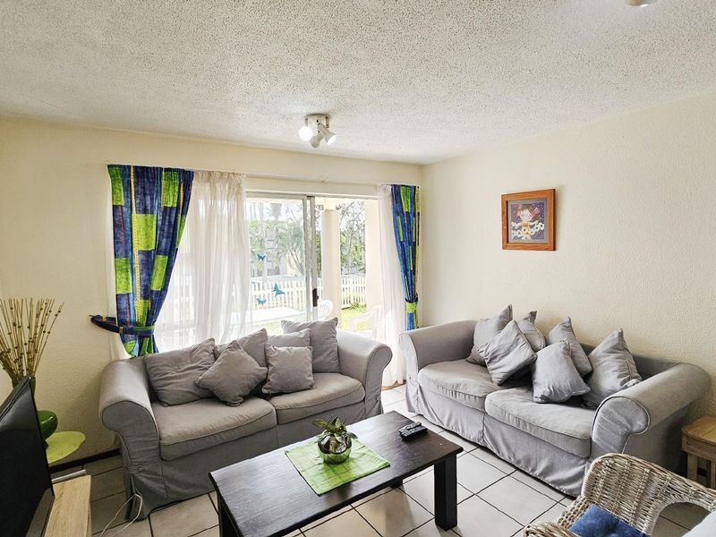 A living room featuring tiled flooring and sliding glass doors that provide access to an outdoor patio area.