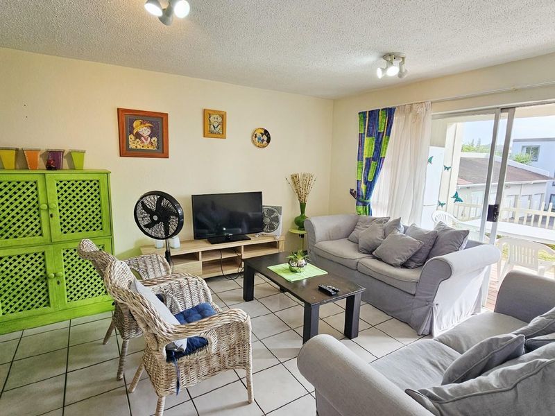 A living room featuring tiled flooring and sliding glass doors that provide access to an outdoor balcony area.