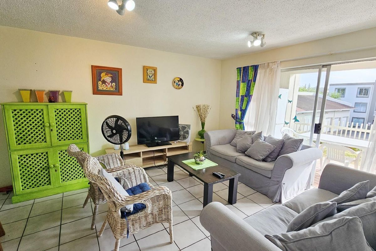 A living room featuring tiled flooring and sliding glass doors that provide access to an outdoor balcony area.