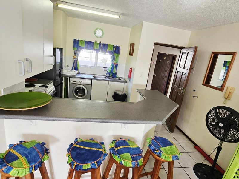 Open plan kitchen featuring a breakfast bar, built-in cabinetry, and integrated laundry plumbing, connecting seamlessly to the living area.