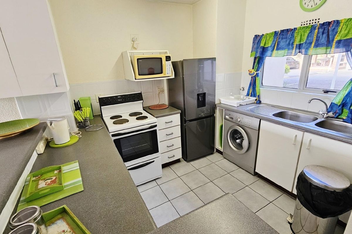 A functional kitchen featuring white cabinetry, tiled flooring, a built-in stove, and integrated space for laundry appliances.