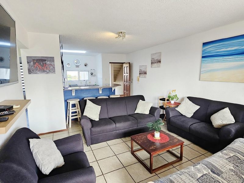 Open-plan living area featuring tiled flooring, a breakfast bar counter, and a connected kitchen space with built-in cabinetry.