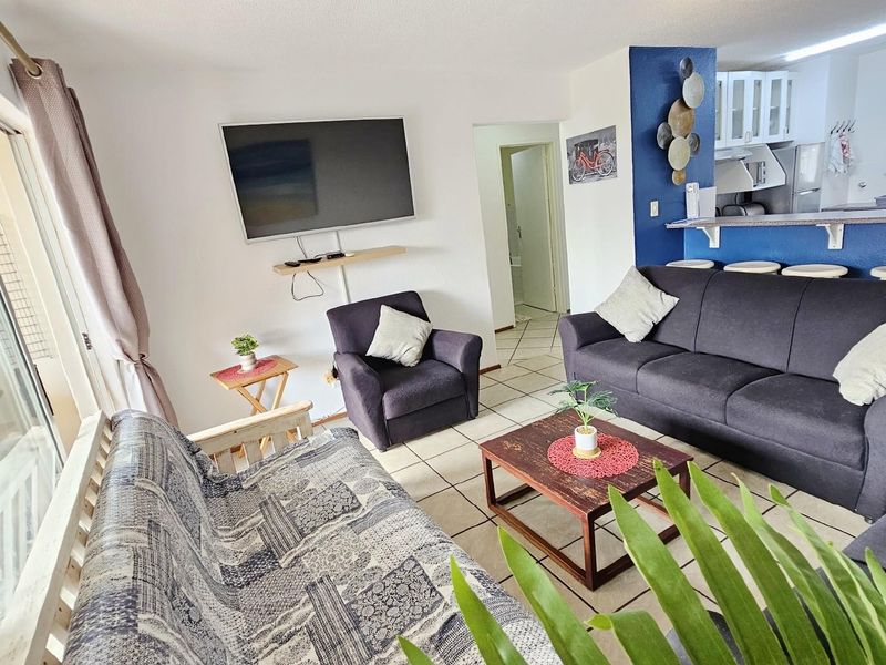 Open plan living area featuring tiled flooring, a breakfast bar counter, and direct access to an outdoor patio through sliding glass doors.