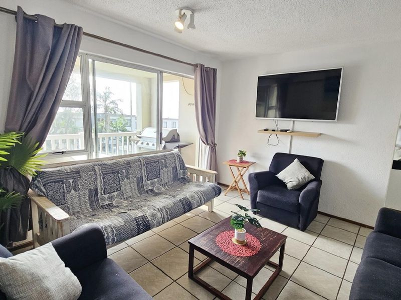 A comfortable living room featuring large sliding glass doors that open onto a private balcony, providing natural light and outdoor access.