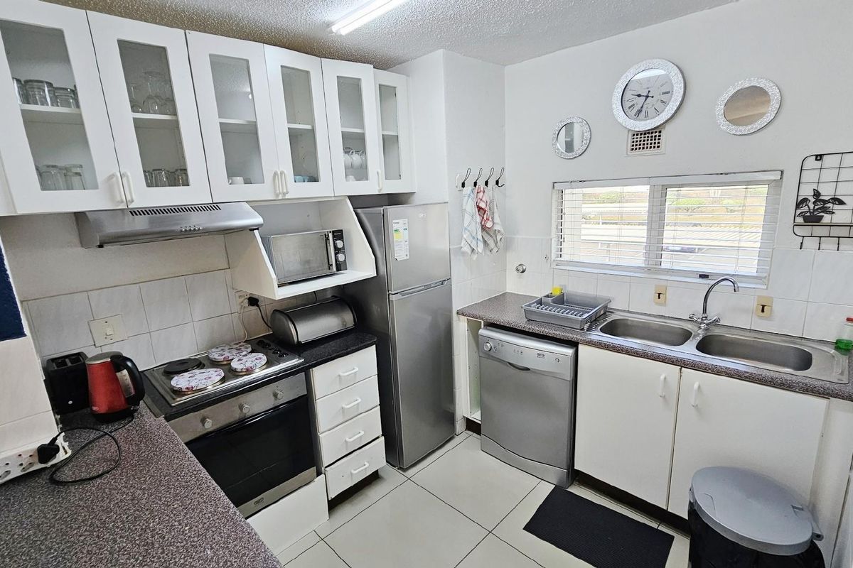 Functional kitchen featuring white cabinetry, built-in oven, hob, extractor fan, double stainless steel sink, and tiled flooring.