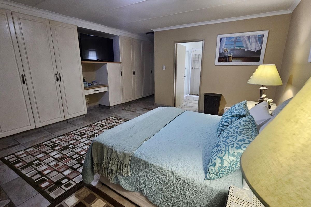 Spacious bedroom featuring extensive built-in cabinetry, tiled flooring, and an en-suite bathroom access.