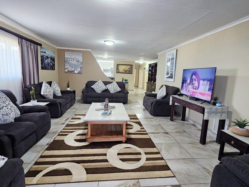 Spacious open-plan living area featuring tiled flooring, neutral wall tones, and a seamless flow towards the kitchen and dining space.