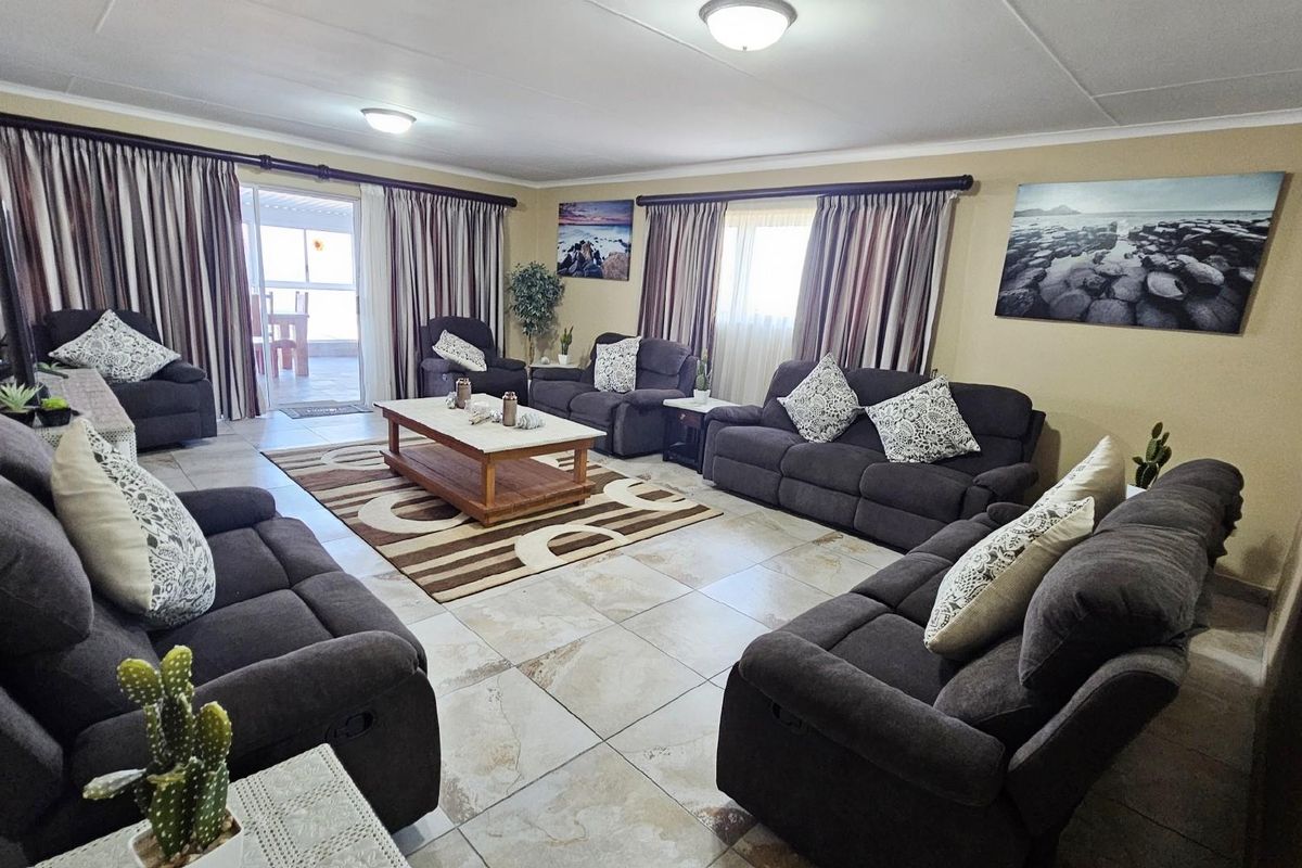 Spacious living room featuring large format floor tiles, neutral wall tones, and direct access to an outdoor patio area.