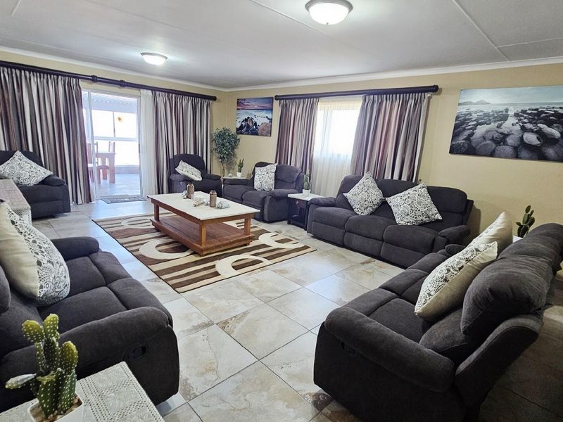 Spacious living room featuring large format floor tiles, neutral wall tones, and direct access to an outdoor patio area.