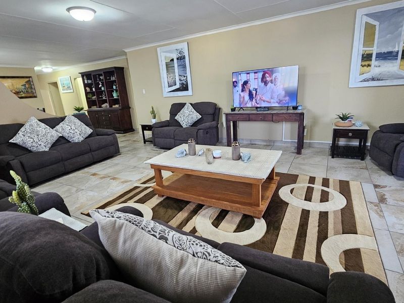 Spacious open-plan living area featuring neutral wall tones and large format floor tiles, providing a comfortable and versatile space for relaxation.