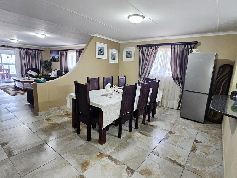 Open-plan living and dining area featuring tiled flooring, a partial partition wall, and direct access to a balcony.