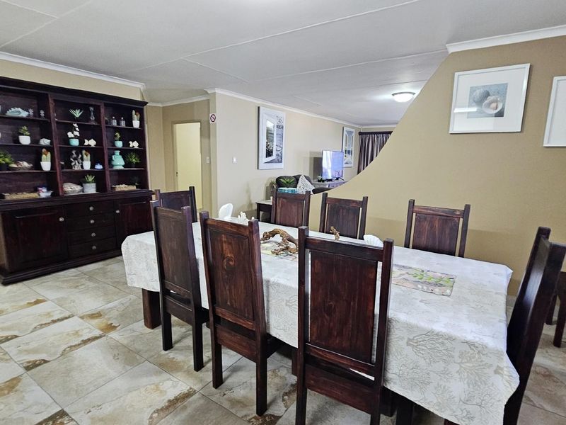 Open plan dining area featuring tiled flooring and a built-in display cabinet, seamlessly connecting to the adjacent living space.