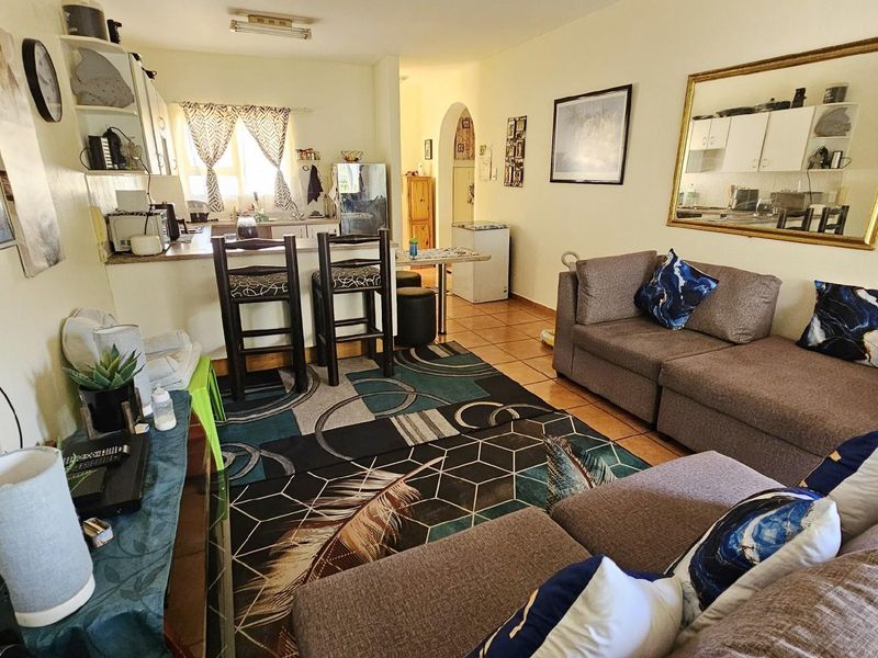 Open-plan living area featuring a kitchen with breakfast bar, tiled flooring, and a connected lounge space.