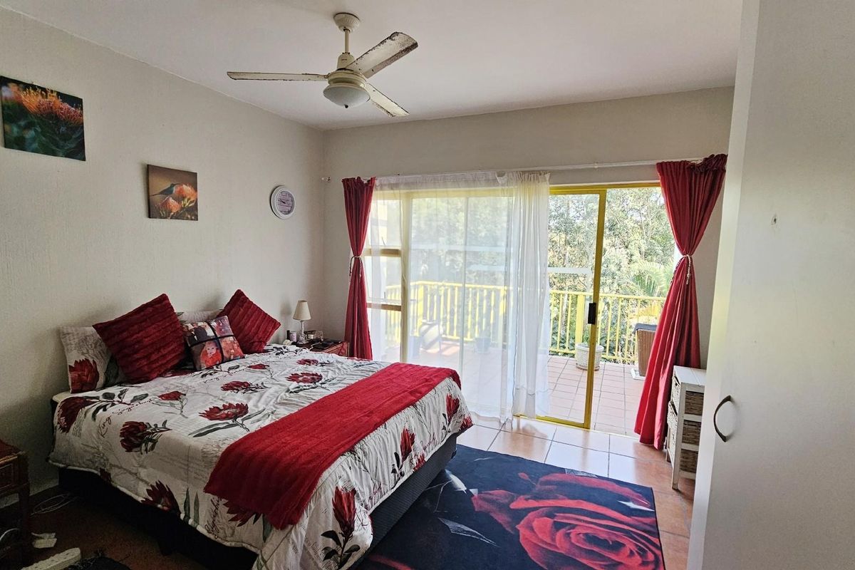 Spacious bedroom featuring a ceiling fan and large sliding glass doors that open onto a private balcony with outdoor views.