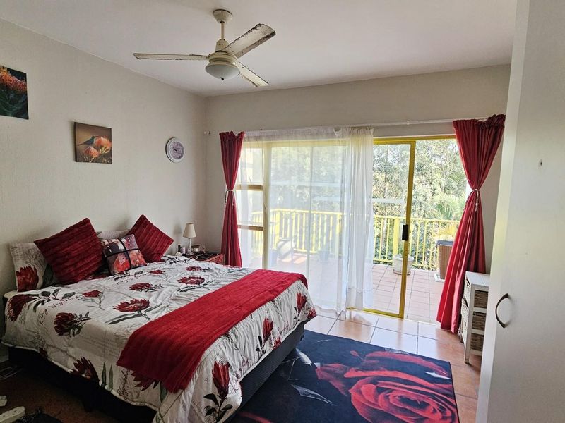 Spacious bedroom featuring a ceiling fan and large sliding glass doors that open onto a private balcony with outdoor views.