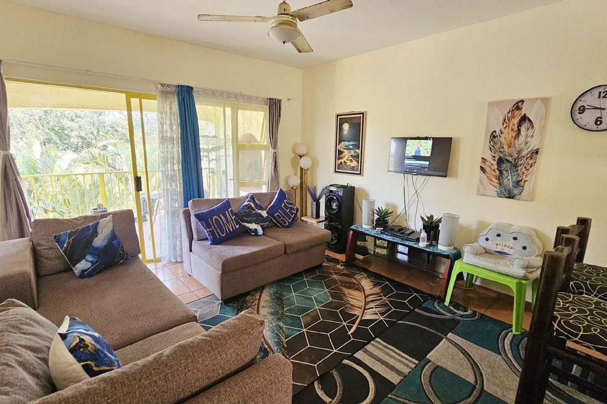 A comfortable living room featuring a ceiling fan and large sliding glass doors that provide access to an outdoor balcony area.