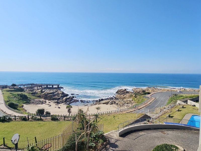 Elevated coastal view overlooking the ocean, rocky shoreline, and local beach area from the apartment balcony.
