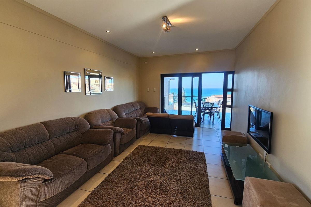 Spacious living area featuring tiled flooring and large glass sliding doors that open onto a balcony with scenic ocean views.