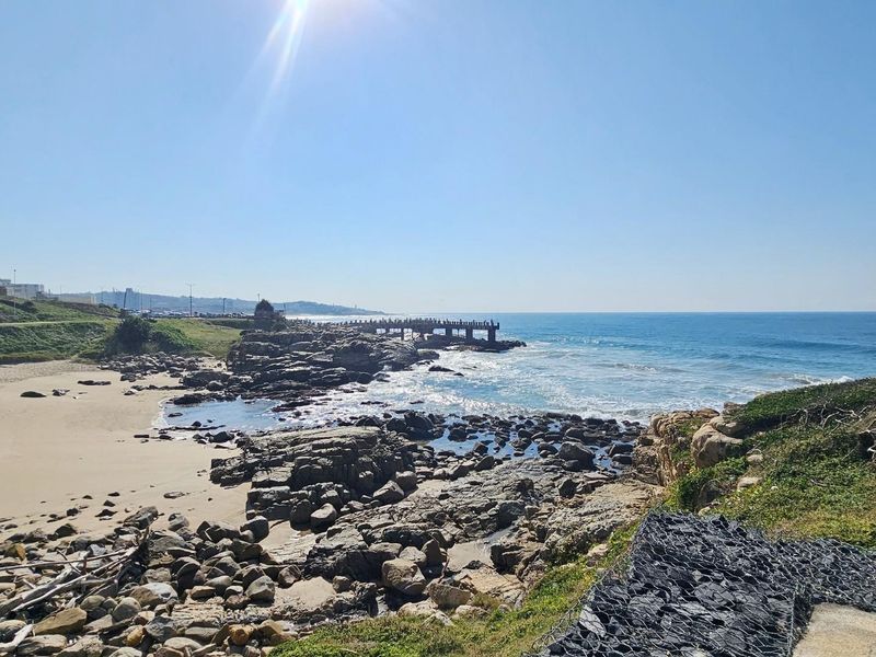 A scenic coastal view overlooking a rocky beach, shoreline, and ocean, highlighting the property's prime location and natural surroundings.