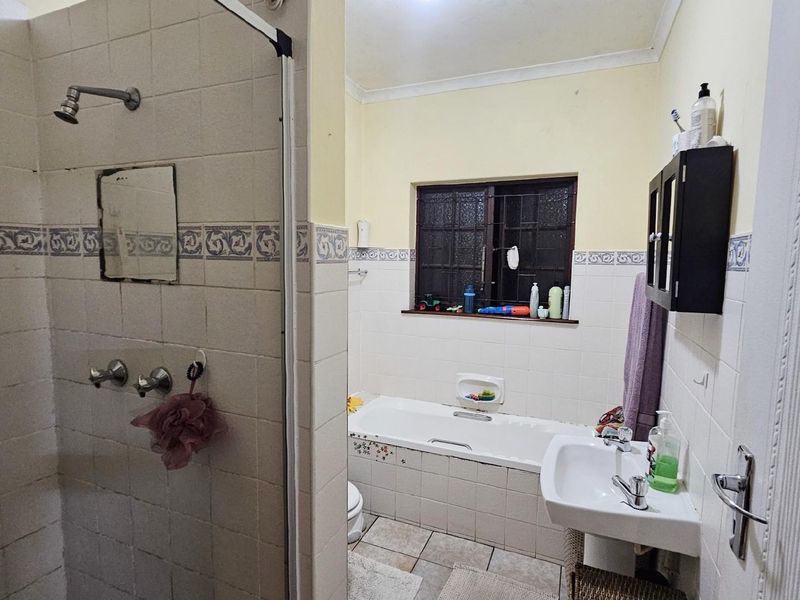 A functional bathroom featuring a separate shower enclosure, a built-in bathtub, and a pedestal basin with tiled walls.