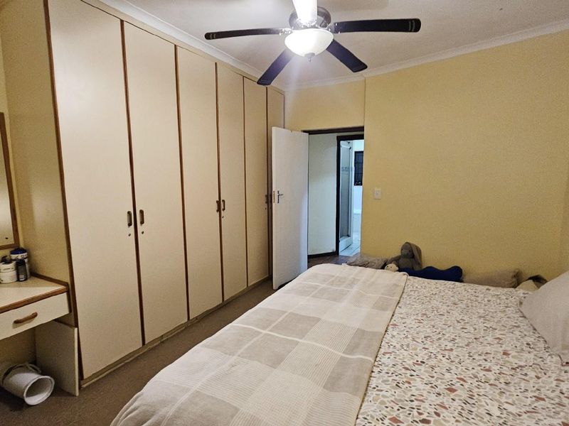 A bedroom featuring extensive built-in cabinetry with integrated vanity and a ceiling fan, providing ample storage and functional space.