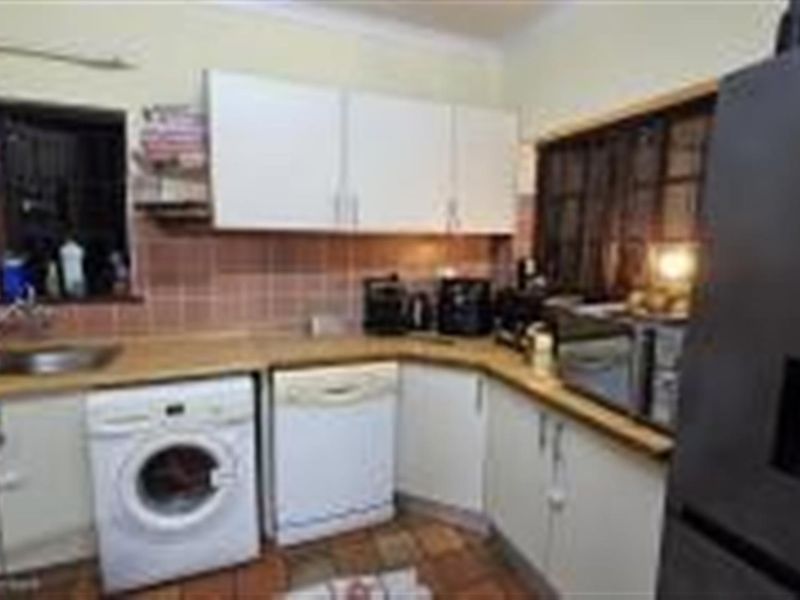 A functional kitchen featuring built-in cabinetry, tiled splashbacks, integrated appliance spaces, and a double basin sink.