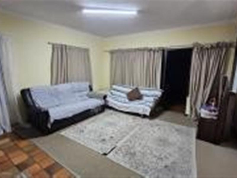 A living room area featuring mixed flooring, including tiled and carpeted sections, with access to an outdoor space through sliding doors.