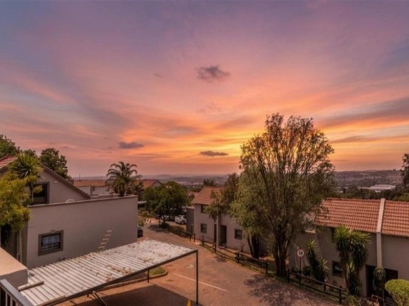 Elevated view overlooking the residential complex and surrounding landscape at sunset, featuring paved driveways and established trees.