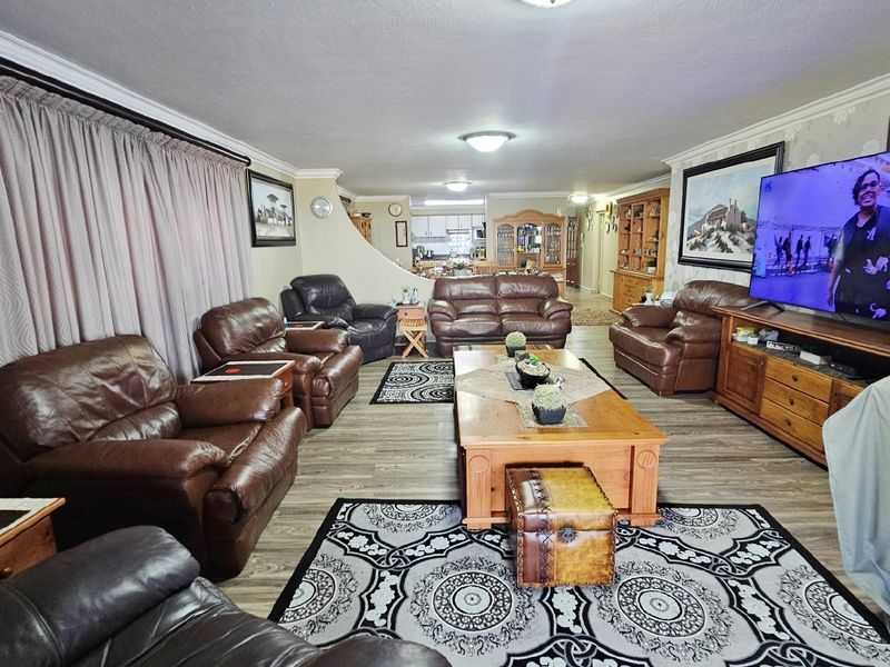 Spacious open-plan living area featuring wood-look flooring, decorative crown molding, and a seamless transition into the kitchen and dining space.