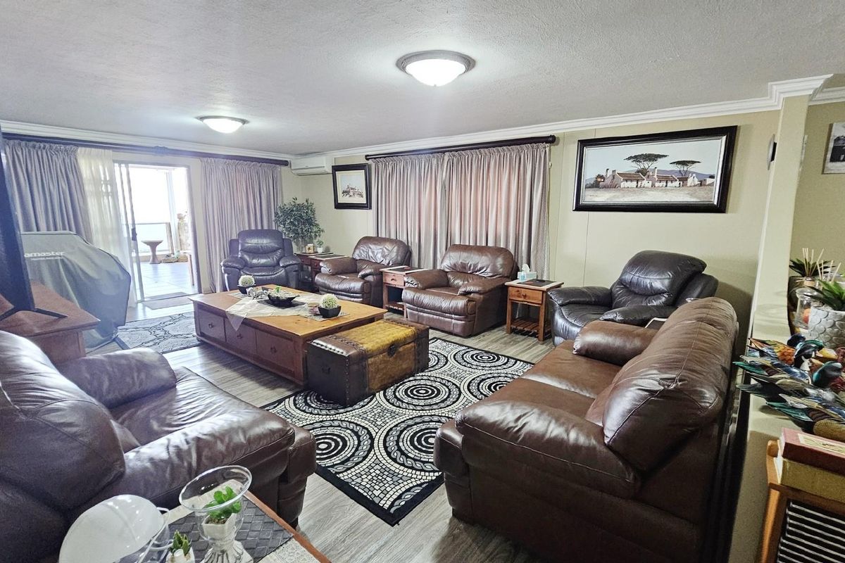 Spacious living room featuring light-toned flooring, crown molding, and sliding glass doors providing access to an outdoor patio area.