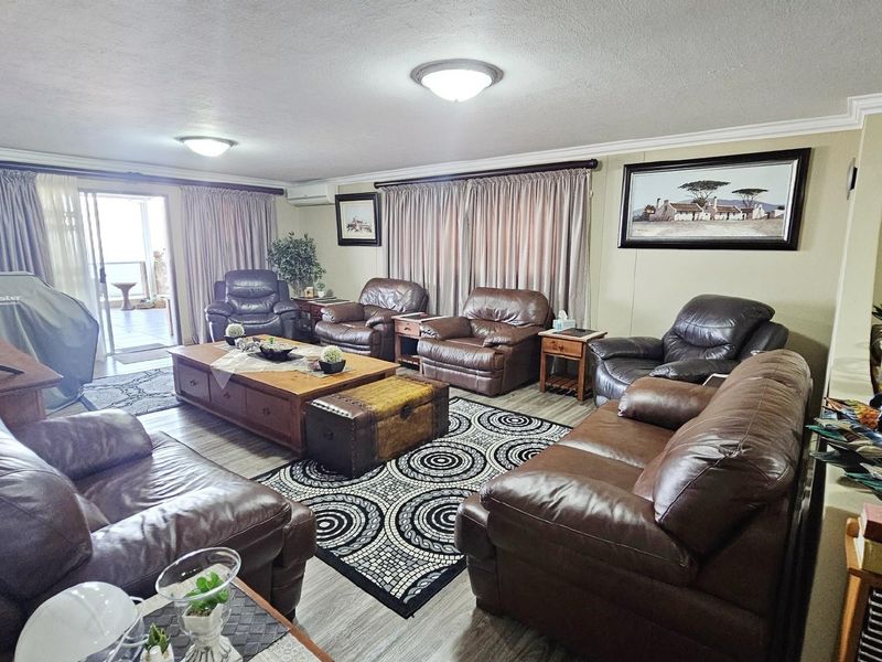 Spacious living room featuring light-toned flooring, crown molding, and sliding glass doors providing access to an outdoor patio area.