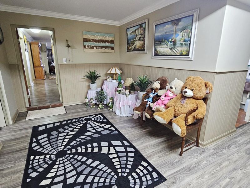 A spacious hallway featuring wood-look laminate flooring and wainscoting, providing access to adjacent rooms within the apartment.