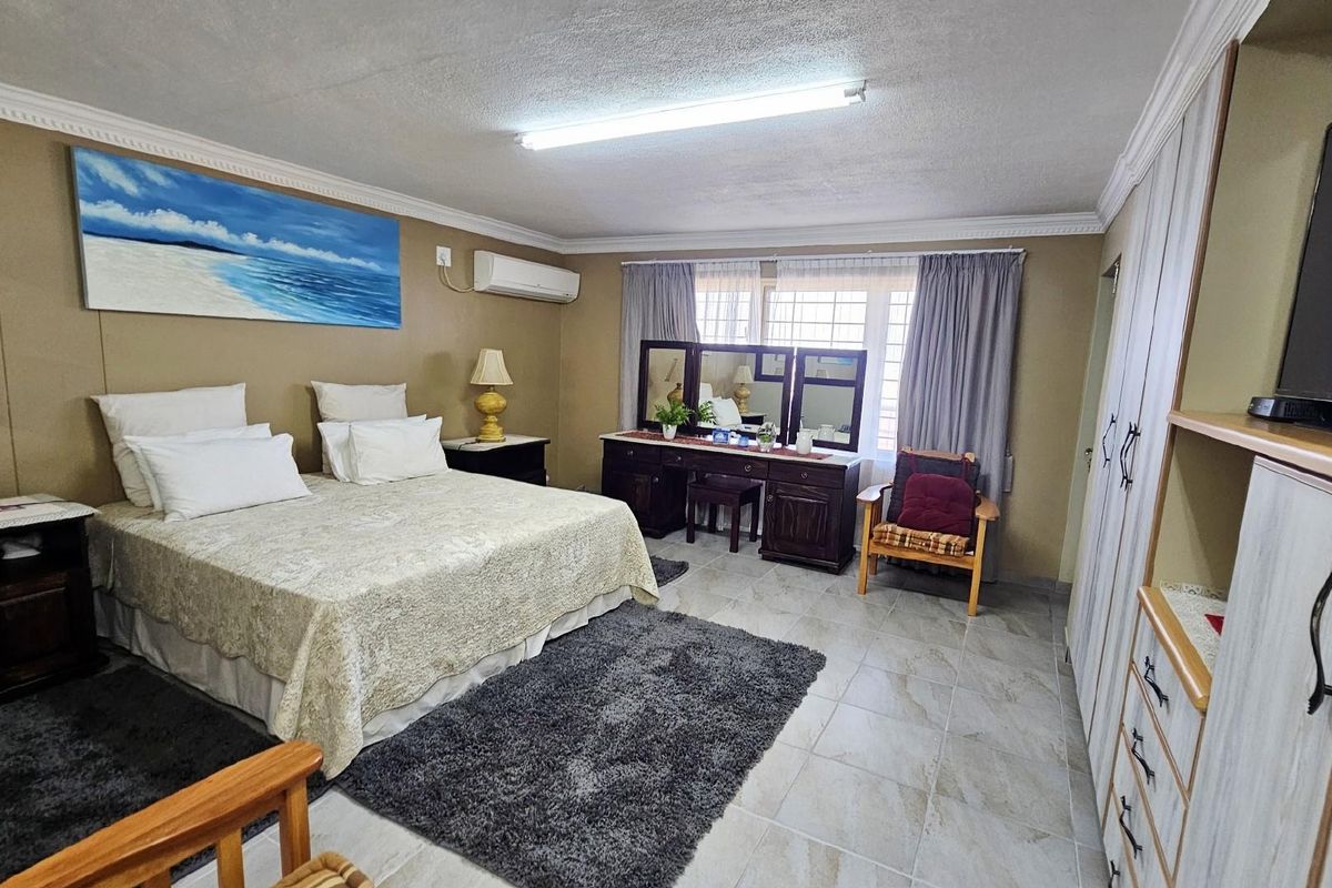 Spacious bedroom featuring tiled flooring, built-in cupboards, and a wall-mounted air conditioning unit.