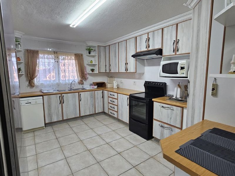 A functional kitchen featuring wood-grain laminate cabinetry, tiled flooring, a built-in oven with extractor fan, and a double-basin sink.