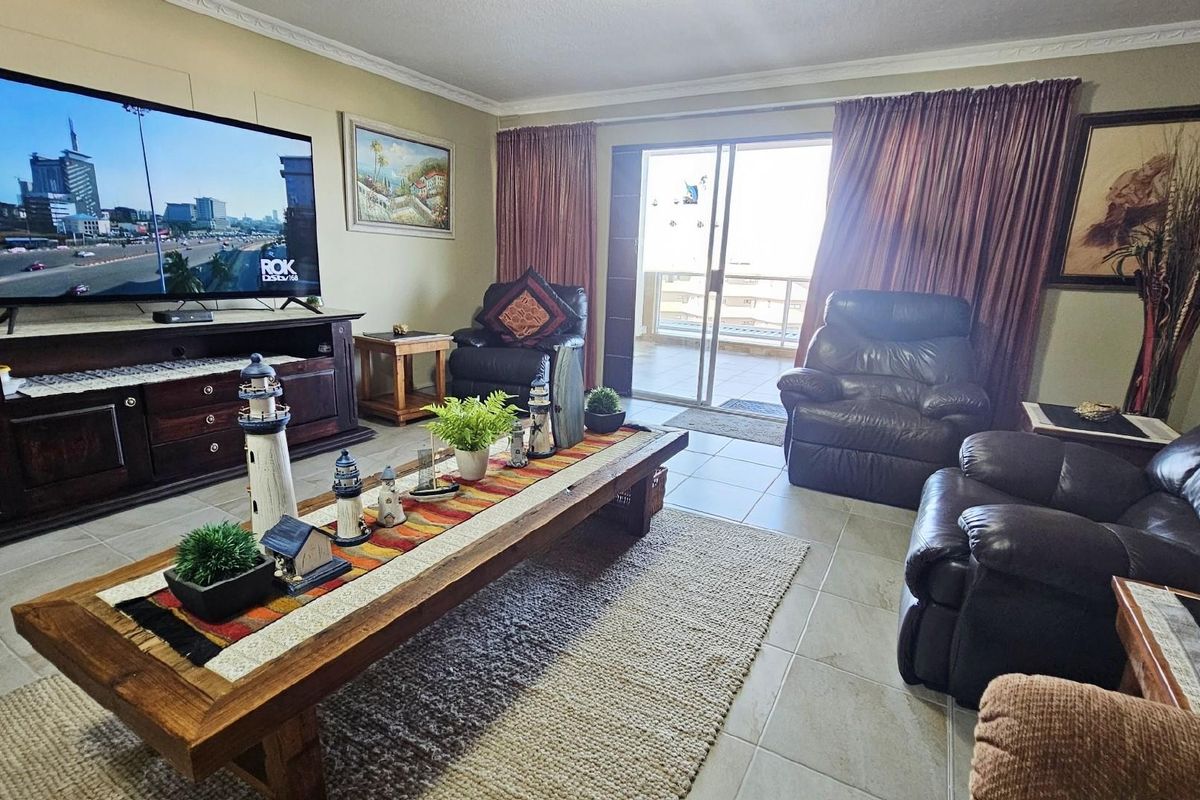 A comfortable living room featuring tiled flooring, crown molding, and sliding glass doors that provide access to an outdoor balcony area.