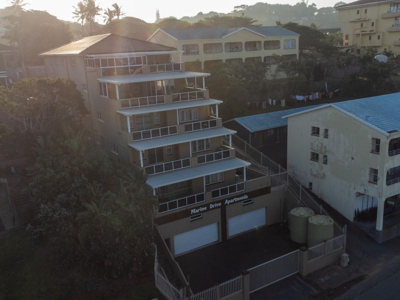 Aerial view of Marine Drive Apartments, a multi-story residential building featuring tiered balconies and ground-level garage access.