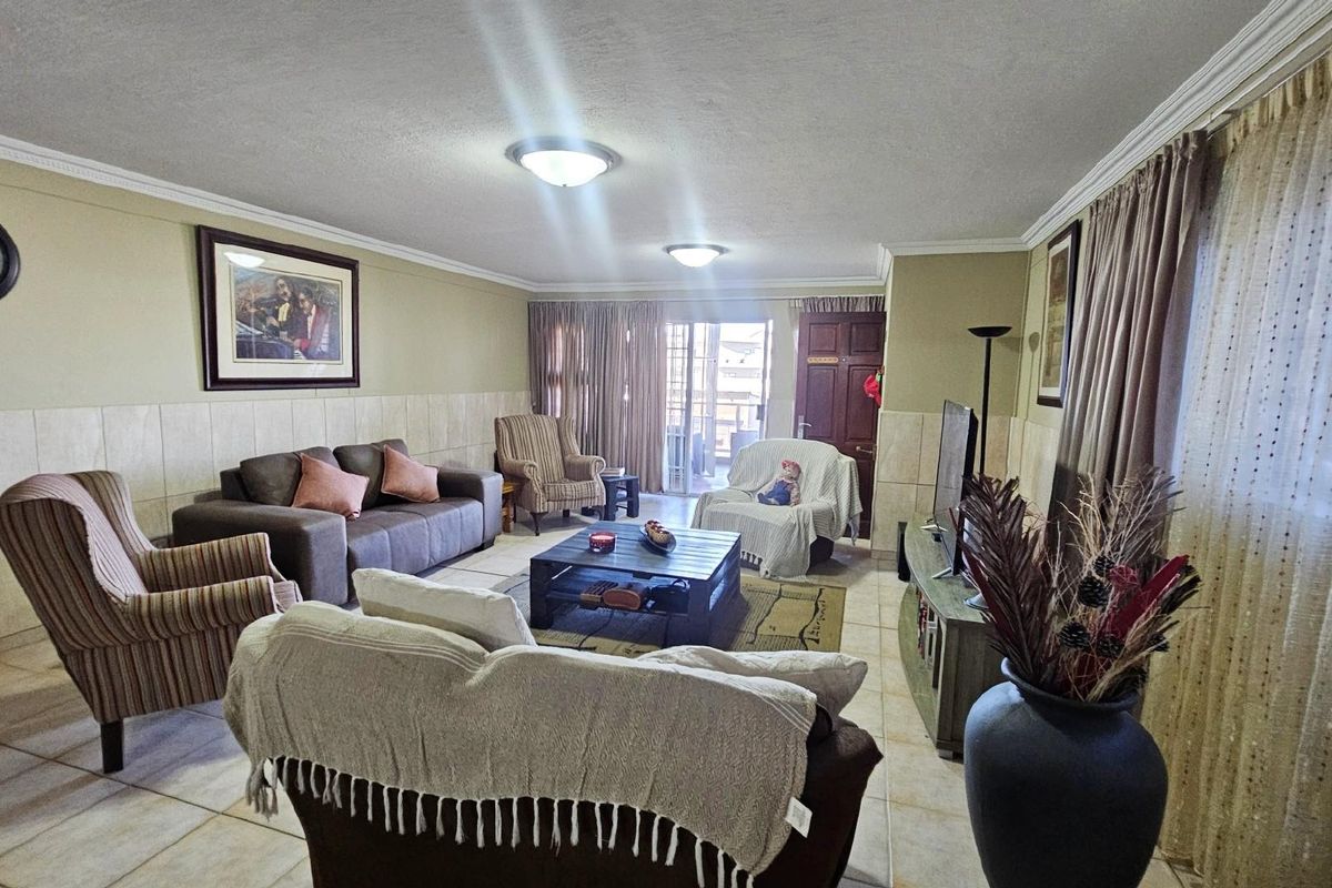 Spacious living room featuring tiled flooring, wall-mounted tiling, and direct access to an outdoor balcony area.